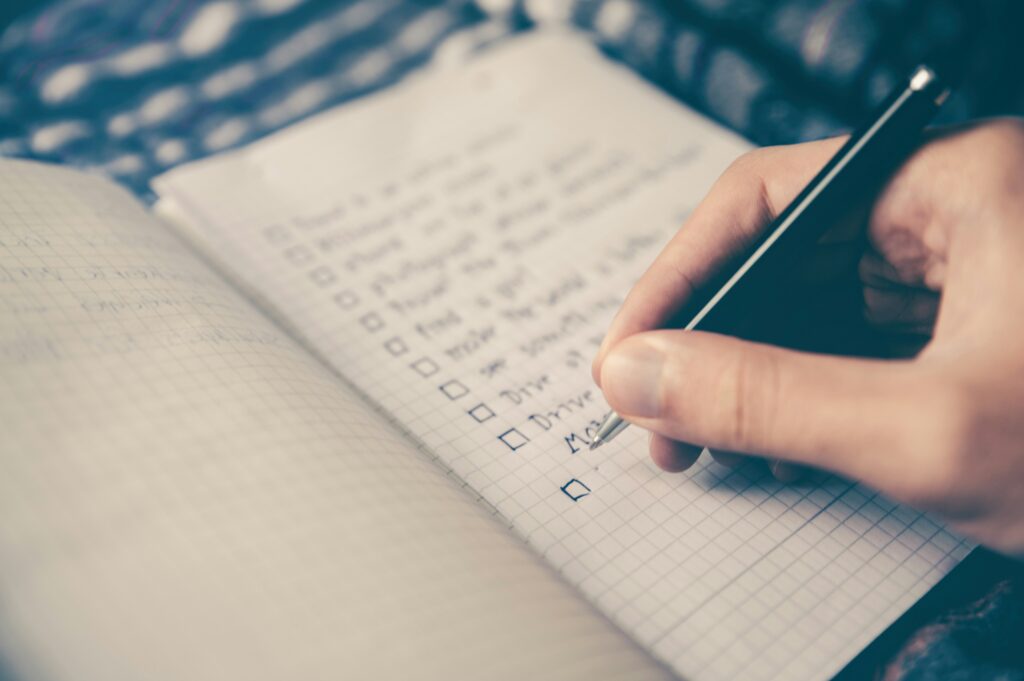 Person writing checklist in notebook