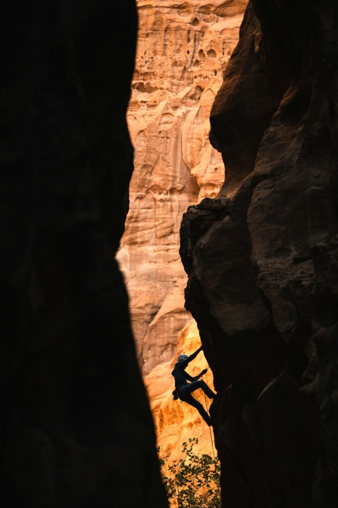 Rock climber ascends steep canyon wall