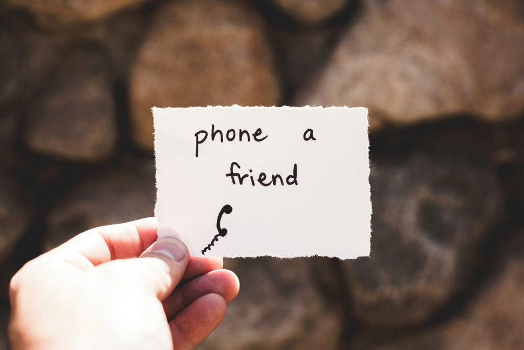 Hand holding note: Phone a friend