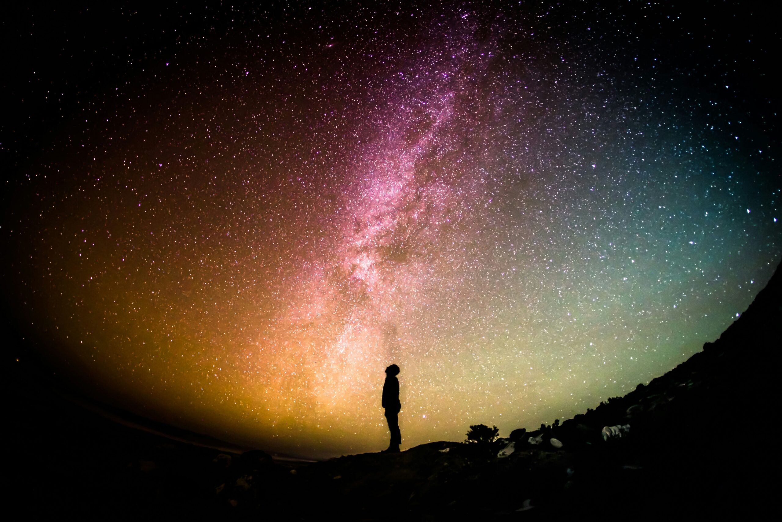 Silhouette under colorful starry sky and Milky Way.