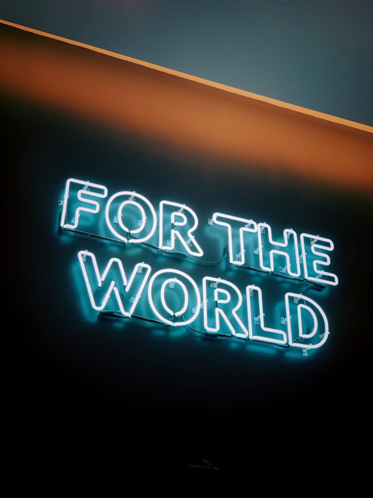 Neon sign displaying 'FOR THE WORLD' on wall.