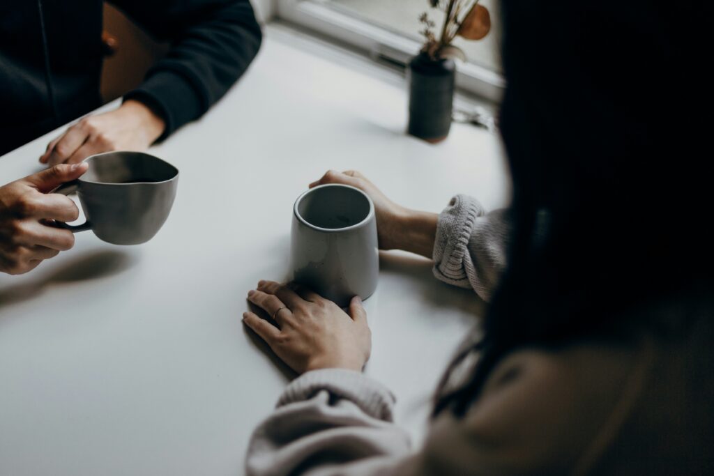 Two people having a conversation over coffee cups.