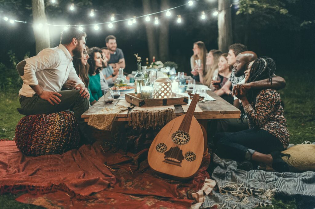 Group enjoying outdoor dinner under string lights.