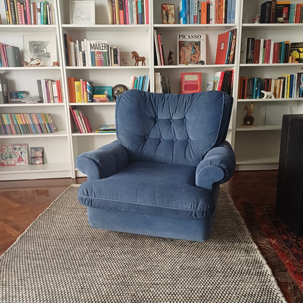 Blue armchair in front of bookshelves.