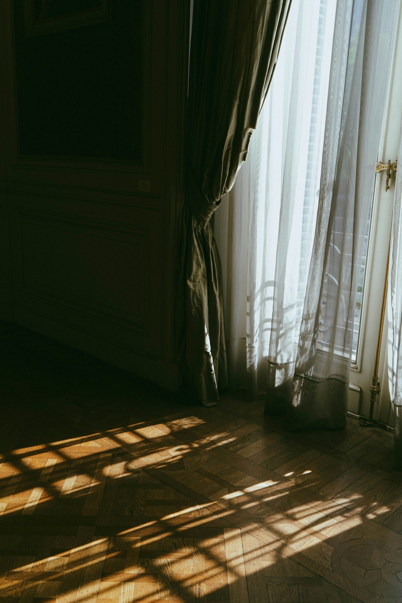 Sunlight through sheer curtains on wooden floor